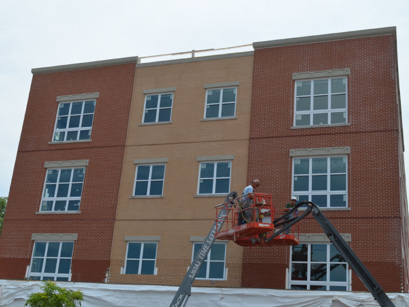 workers finishing a thin brick install on the exterior of a commercial building