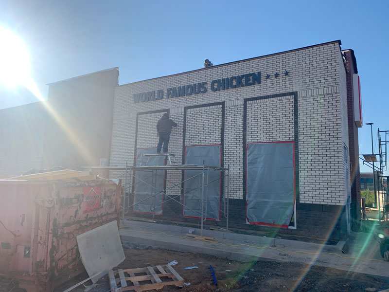 worker installing thin brick on exterior walls of a KFC