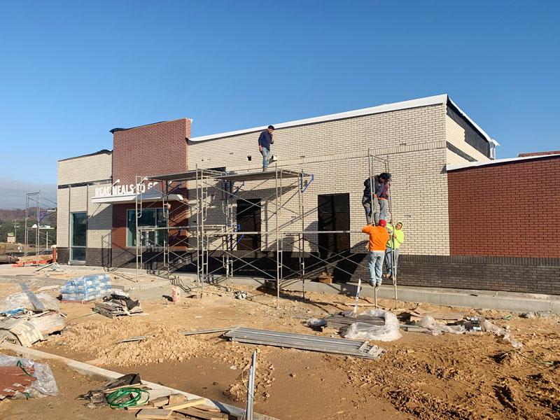 workers installing thin brick onto exterior of a new KFC franchise location